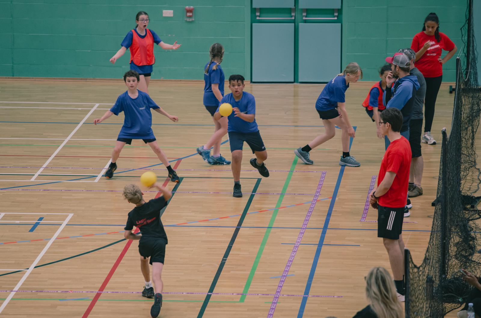 Children playing dodgeball in a school sports hall